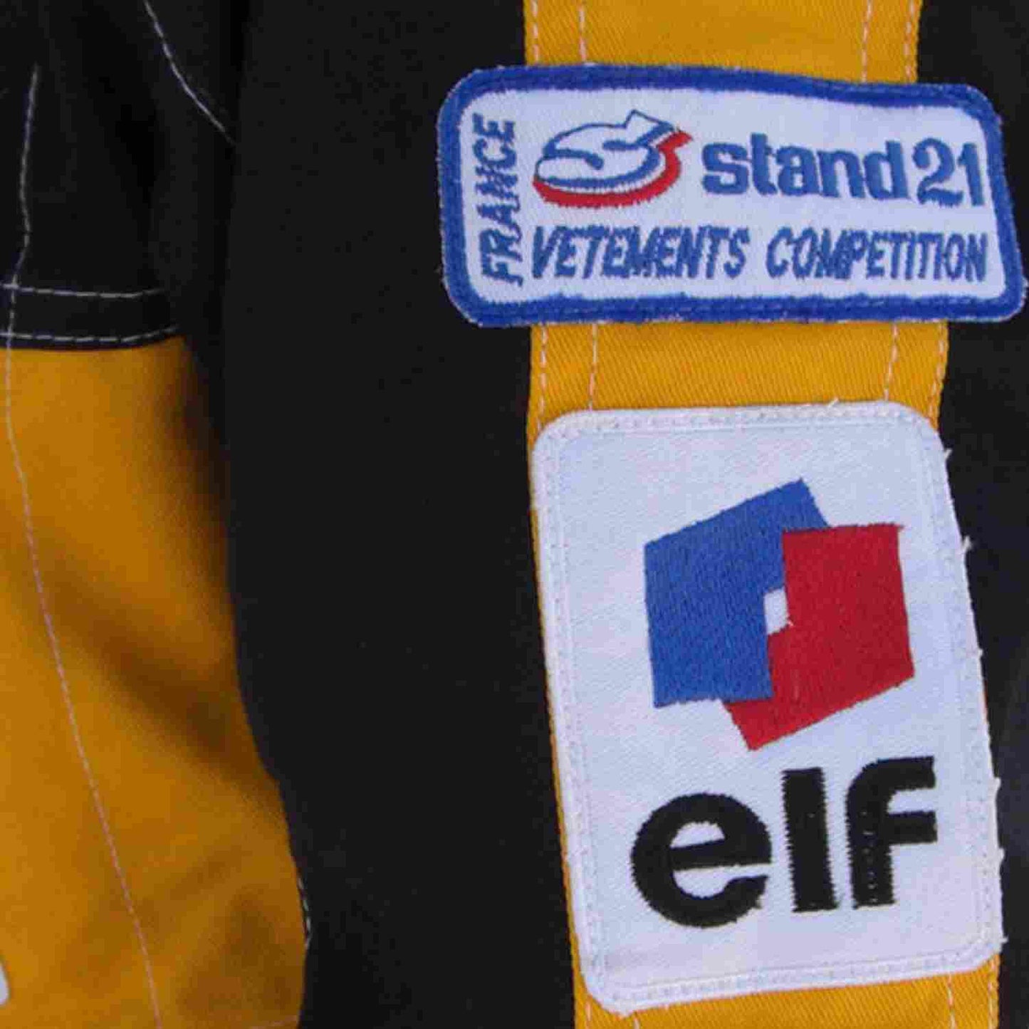 Close-up detail of the Ayrton Senna 1985 F1 racing suit fabric and stitching, showcasing vintage craftsmanship and sponsor detailing.