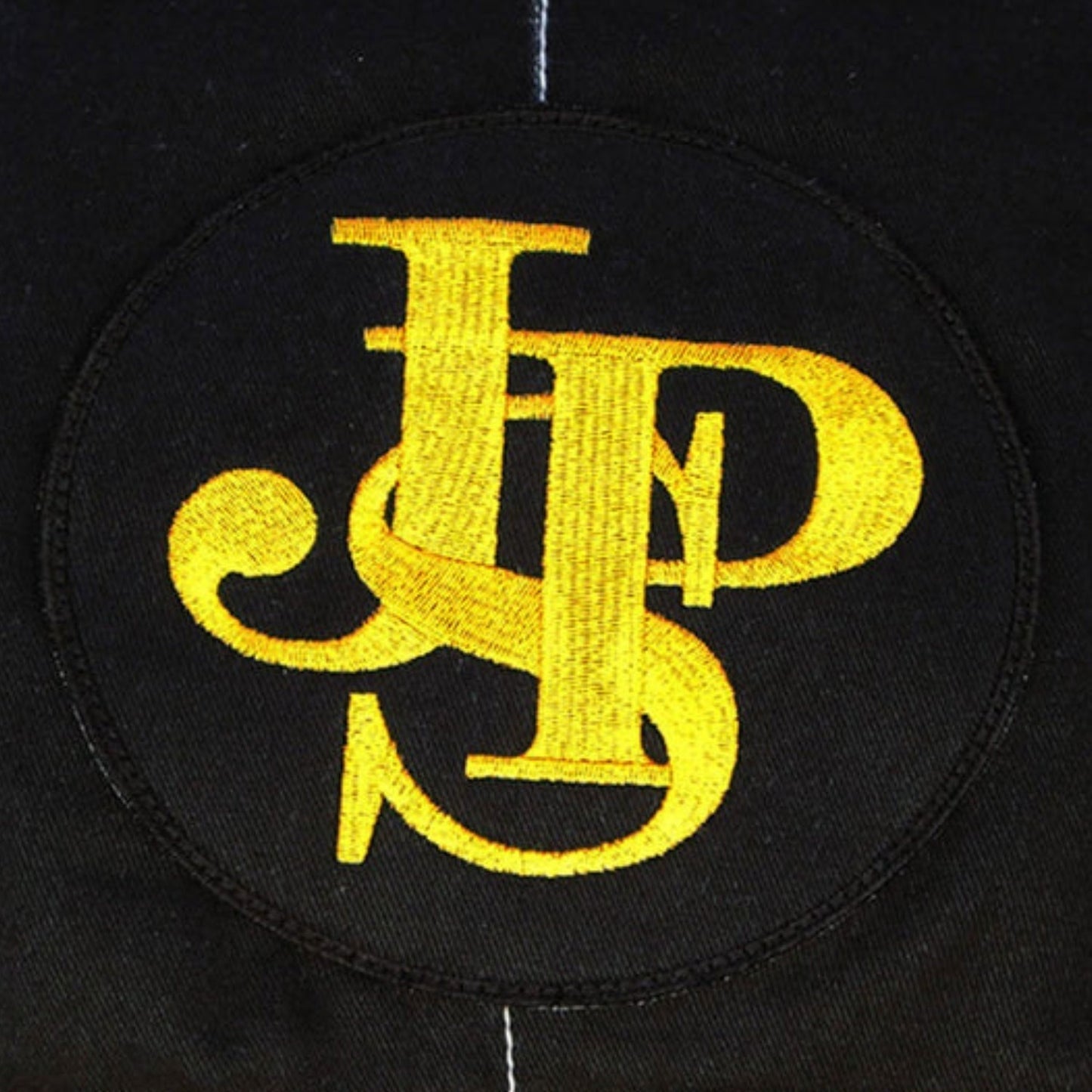 Close-up detail of the Ayrton Senna 1985 F1 racing suit fabric and stitching, showcasing vintage craftsmanship and sponsor detailing.