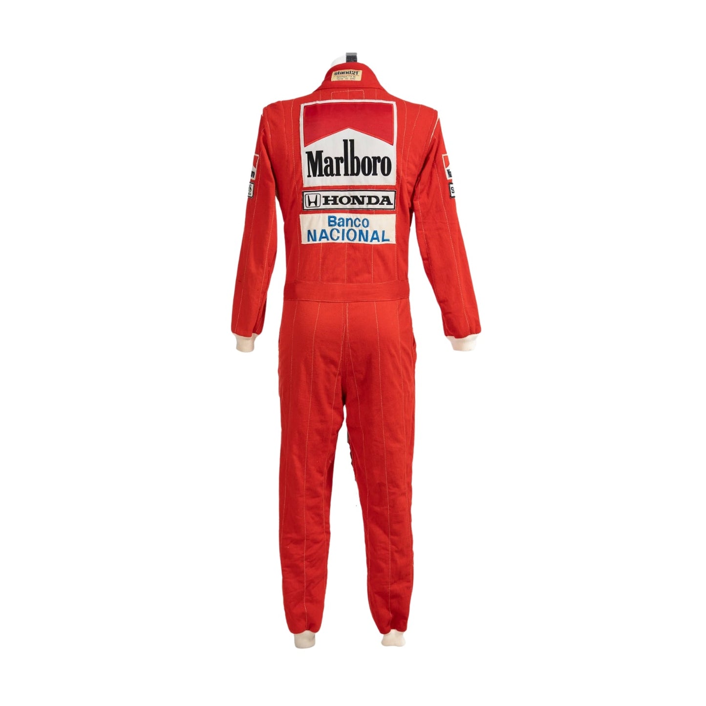 Back of Ayrton Senna’s 1988 F1 racing suit, showcasing the iconic red and white color combination and classic sponsor designs that marked his first world title.