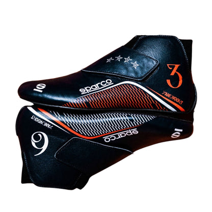 A pair of Sparco racing shoes in black leather with orange and white graphics, including the number 3 and the name Jank Woolf.
