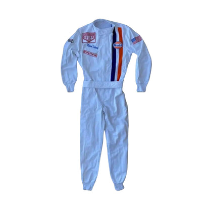 Front view of Michael Delaney’s 1971 Le Mans racing suit worn by Steve McQueen, featuring off-white base, vertical Gulf racing stripes in blue and orange, and vintage patchwork detailing.