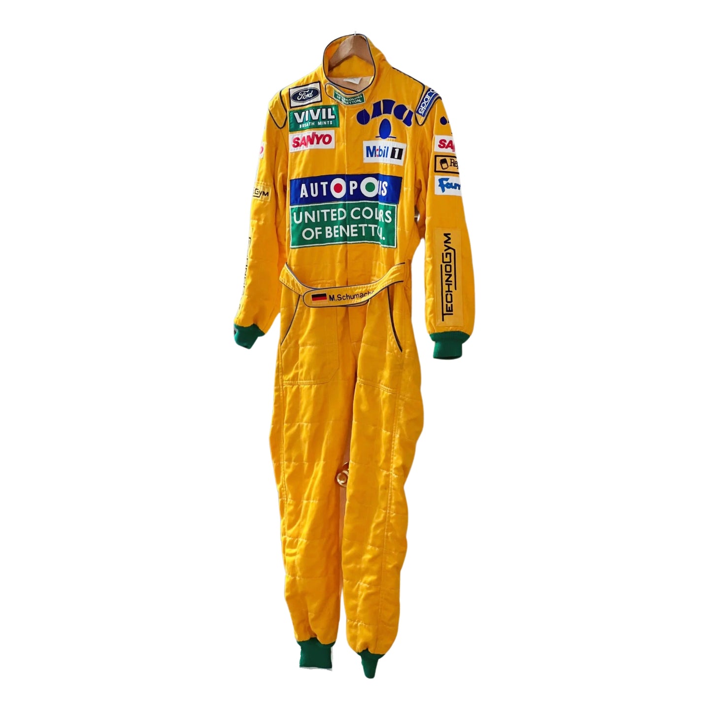 Front view of Michael Schumacher's 1992 F1 racing suit featuring deep green with yellow accents, signature Benetton sponsorship, and classic zip-front design.